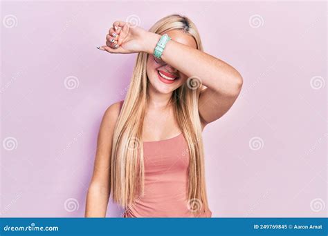 Young Blonde Girl Wearing Casual Clothes Covering Eyes With Arm Smiling