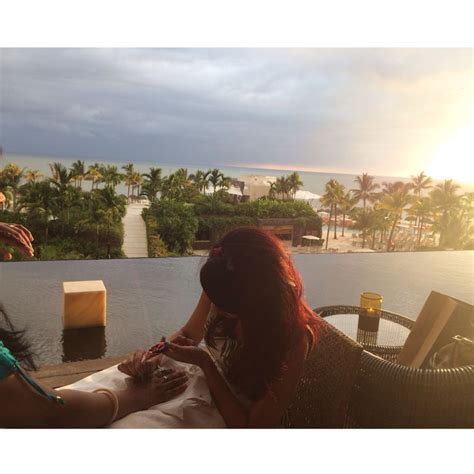 Two Women Sitting At A Table In Front Of A Pool With The Sun Shining On