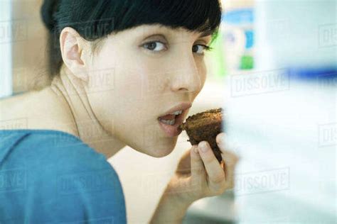 Woman Eating Piece Of Chocolate Cake Looking Over Shoulder At Camera