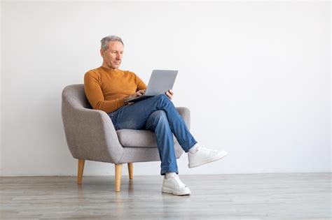 Premium Photo Confident Mature Man Using Laptop Sitting On Chair