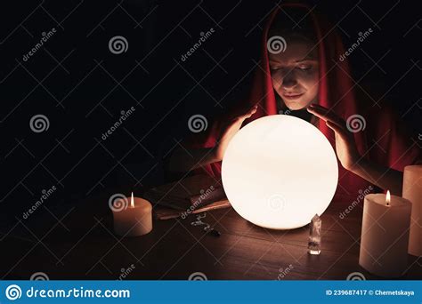 Soothsayer Using Glowing Crystal Ball To Predict Future At Table In