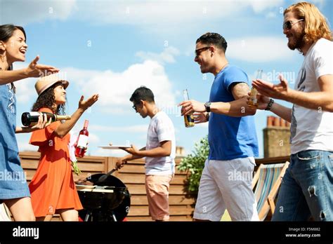 Saludo amigos femeninos y masculinos en la barbacoa de la azotea ...