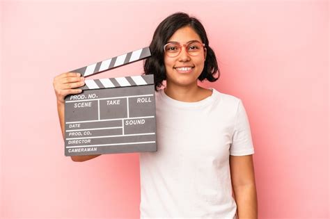 Joven Latina Sosteniendo Claqueta Aislada Sobre Fondo Rosa Feliz Sonriente Y Alegre Foto Premium