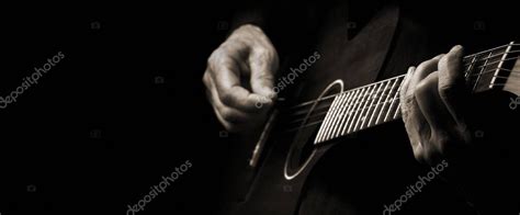 Tocando una guitarra acústica Las manos del guitarrista y la guitarra