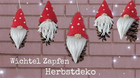 Three Gnomes Hanging From The Side Of A Brick Wall With Pine Cones