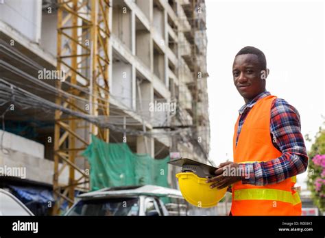 Young Black African Man Construction Worker Holding Clipboard An Stock