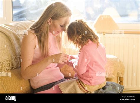 A Young Mother Sitting With 3 Year Old Girl On Her Knee Playing