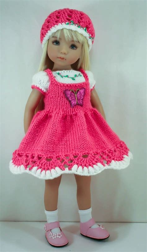 A Doll Wearing A Pink Knitted Dress And Hat With Butterfly On The Chest