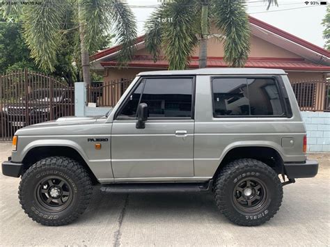 Silver SUV Parked In Front Of A House With Palm Trees Behind It And A Gate