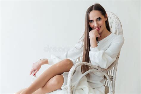 Brunette In White Dress Sits Comfortably In A Chair In A Bright Room Stock Image Image Of Lady