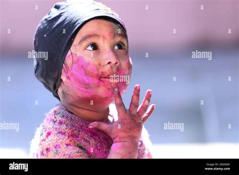 portrait of Kid face full of color while playing with color during holi ...