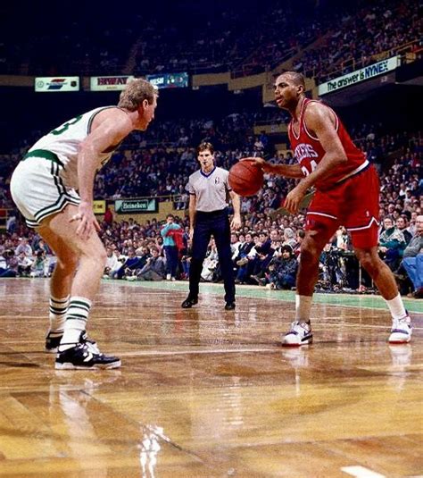 Two Men Playing Basketball On A Court With People Watching From The