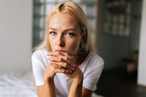 Close Up Face Of Thoughtful Blonde Female Sitting Alone In Living Room And Serious Looking At