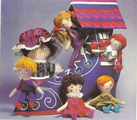 A Group Of Dolls Sitting Next To Each Other In Front Of A Doll House