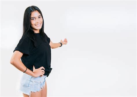 Chica joven feliz dándole la bienvenida aislada chica latina sonriente apuntando hacia atrás