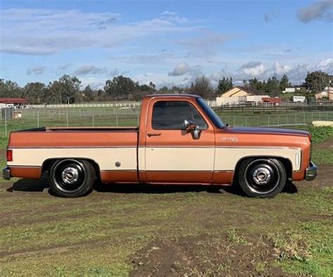 An Orange And White Truck Parked In A Field