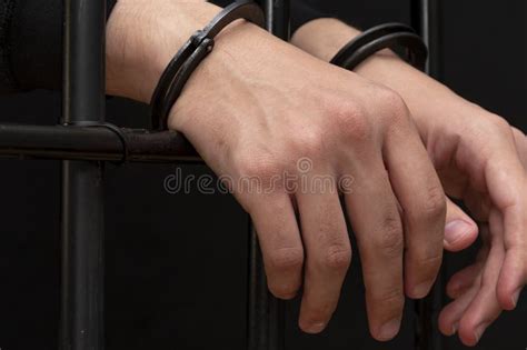 The Hands Of A Young Man In Handcuffs Hang Over The Bars Dark Tone