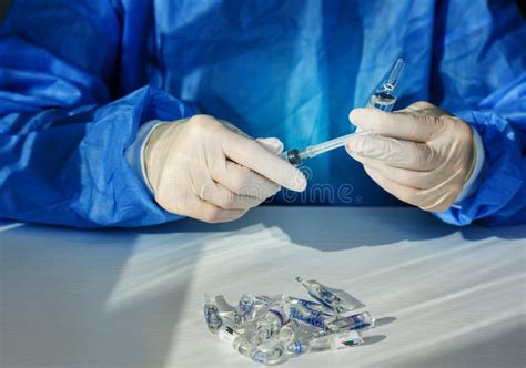 Doctor In A Blue Surgical Gown And Mask Holds In His Hand A Medical