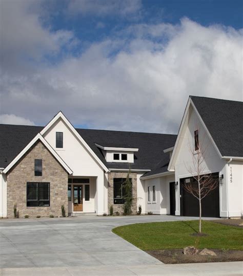 A Large White House With Black Roof And Windows