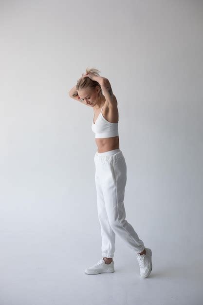 Une Belle Fille Blonde Dans Un Haut Blanc Et Des Collants Posant Sur Un Fond Blanc Photo Gratuite
