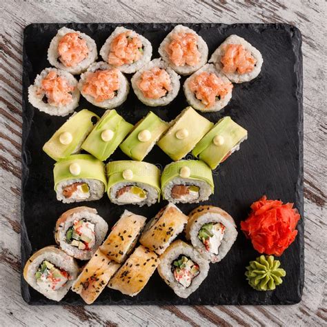 Large Sushi Set Of Various Sushi Rolls Is Served On Black Square Metal