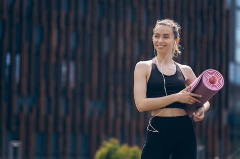 Fille Blonde Avec Queue De Cheval Tenant Un Tapis De Yoga Rose Roul Photo Gratuite