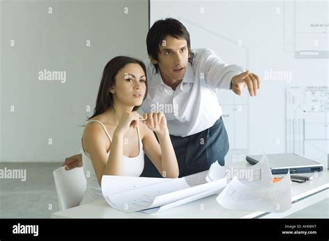 Couple Next To Table With Blueprints Man Leaning Over Womans Shoulder