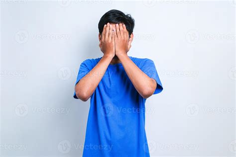 Asian Man With Sad Expression Covering Face With Hands While Crying