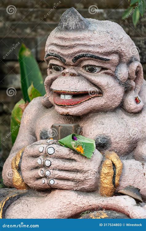 A Statue Sitting In Front Of A Building Holding A Small Plant Editorial