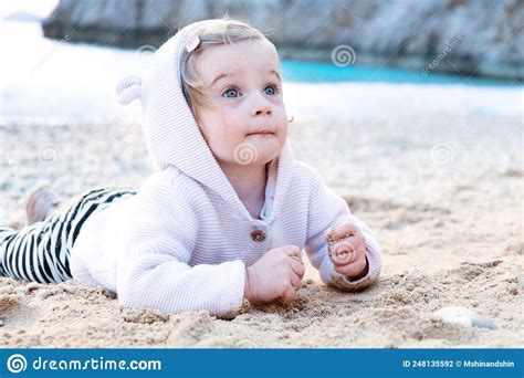 Caucasian Baby Girl Wearing Shirt With Funny Animal Ears On Sandy Beach