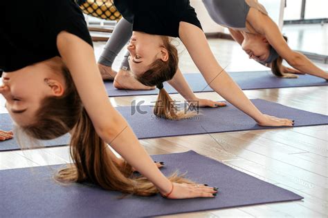 一群穿着运动服的漂亮运动女孩在健身馆锻炼在健身房的垫子上做狗瑜伽姿势锻炼高清摄影大图 千库网