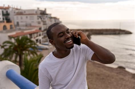 Premium Photo Cheerful Black Man Talking On Cellphone At Beach