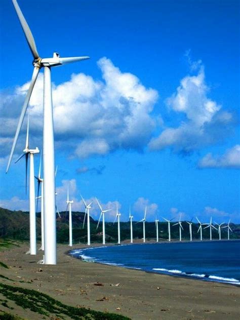 several wind turbines are on the beach by the ocean