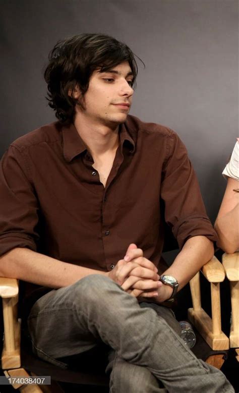 A Young Man Sitting In A Chair With His Hands Folded Up And Looking