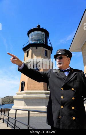 A male guide in traditional lighthouse keepers' uniform posing by the Split Rock Lighthouse ...