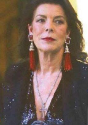 An Older Woman Wearing Red Earrings And A Black Jacket With Sequins On It