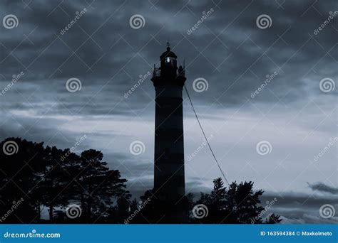 Lighthouse Shines In The Dark With A Dramatic Sky Silhouette Of