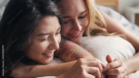 Vidéo Stock Homosexual lesbian couple lying in bed together Take hands and smile each other