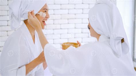 Beautiful young woman in white bathrobe applying a revitalizing white