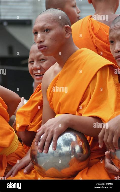 Buddhist Monks Wearing Orange Robes Sit With Their Alms Bowls Near Tha