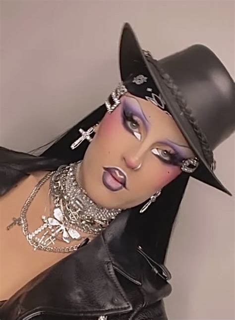 A Woman Wearing A Black Hat And Leather Outfit