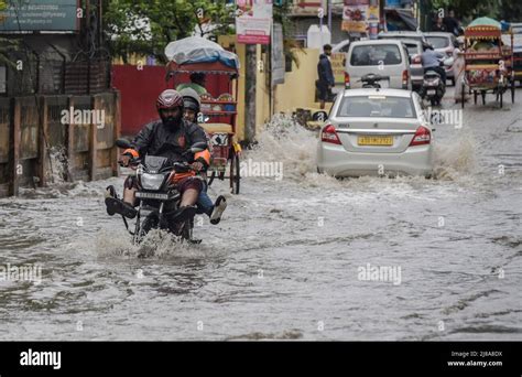 Commuters Make Their Way On A Waterlogged Street After A Heavy Rainfall