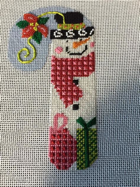 A Cross Stitch Snowman Ornament On A White Background With A Red Flower