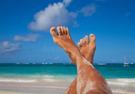 Piernas De La Mujer Joven Que Toman El Sol En La Playa Imagen De