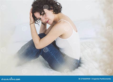 Eine Brunette Mit Lockigem Haar Sitzt Auf Dem Bett Und Umarmt Ihre Knie Stockfoto Bild Von