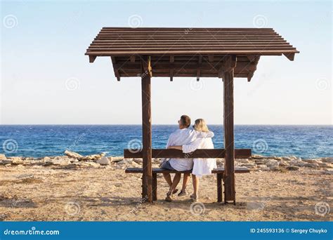 Love Couple Sitting On A Bench By The Sea And Enjoying Beautiful View