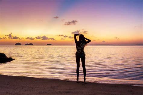 Young Girl Stay On The Beach And Watching The Sunset Stock Photo