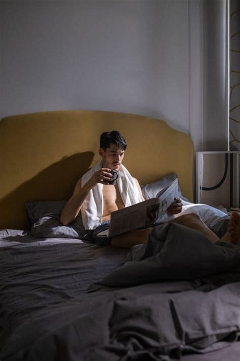 A Man Reading a Newspaper While in Bed · Free Stock Photo