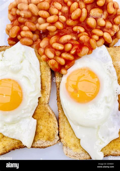 Two fried eggs on toast with baked beans Stock Photo - Alamy