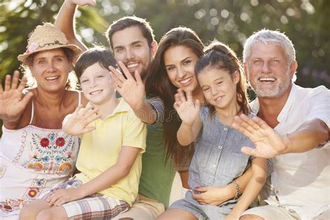 Familia Multi De La Generaci N Que Se Sienta En Jard N Y Agitar Foto De